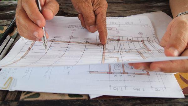 An image showing two hands over a drawing of structural plan.