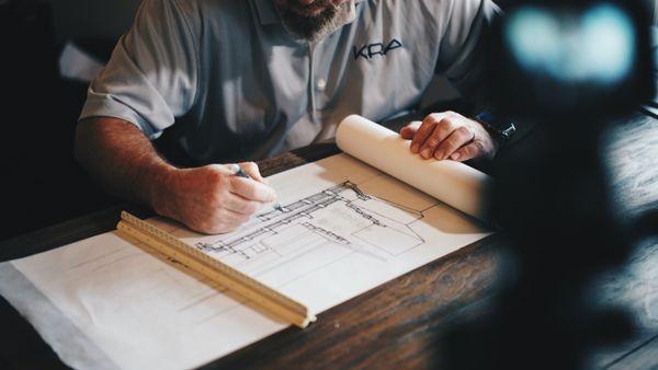 A photo showing an architect working on a draft with a pencil and rule